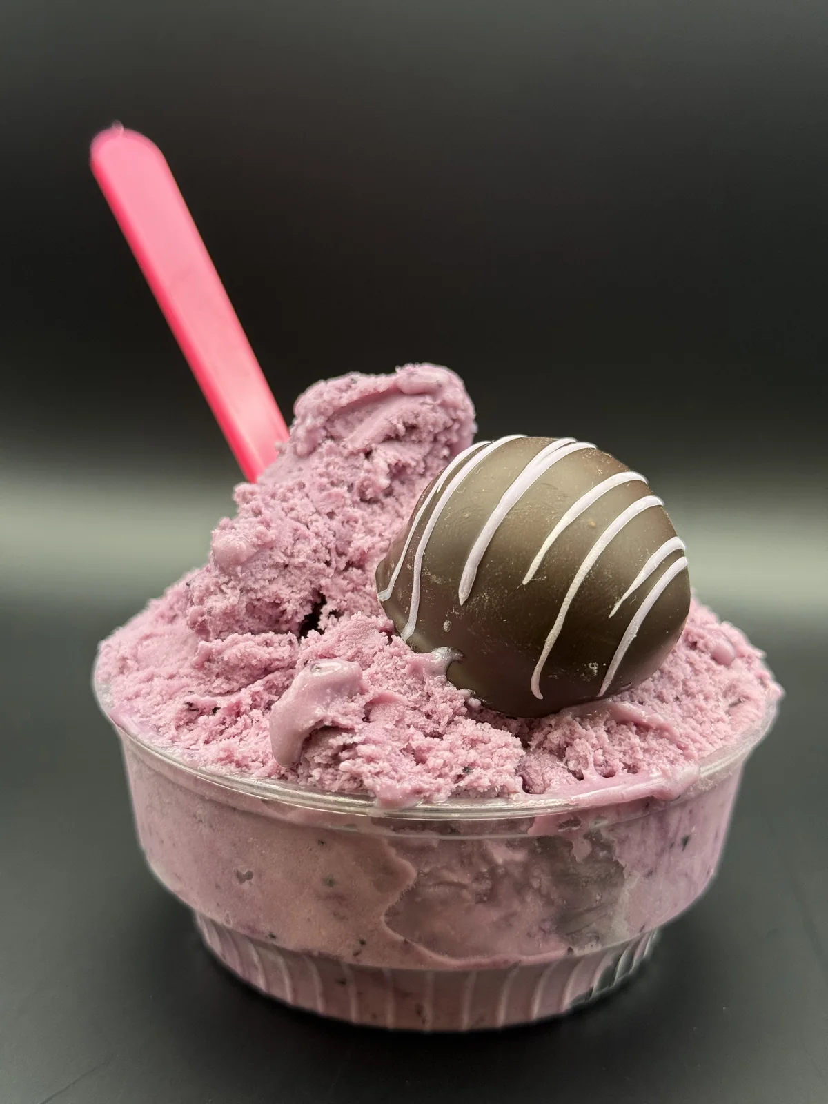 A cup of huckleberry gelato topped with a chocolate confection